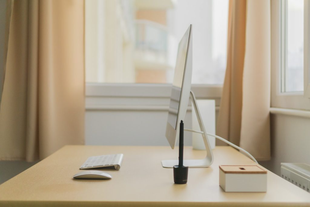 A clean desk with an Apple iMac, keyboard, and pen